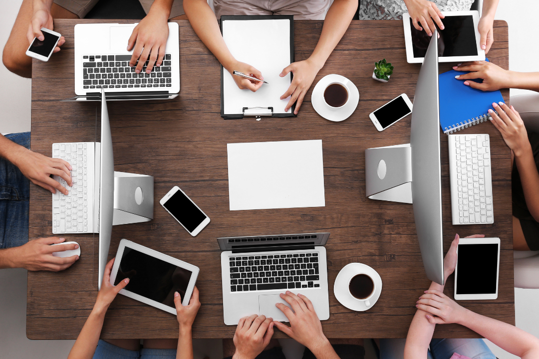 A diverse group of non-tech users working on laptops and tablets, planning content and improving their online presence.